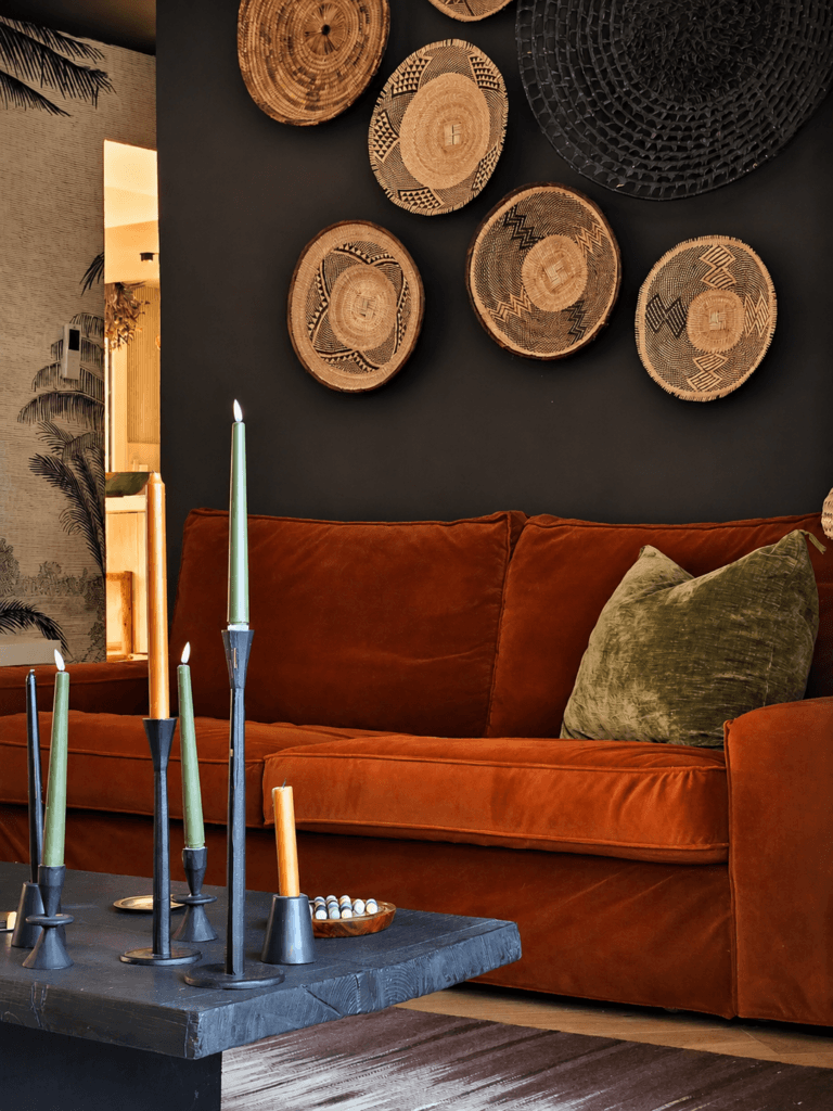 Décoration et rénovation d'un salon contemporain avec canapé terracotta, mur noir et décoration murale en fibres naturelles, réalisée par une décoratrice d'intérieur.